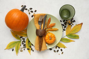 Beautiful table setting with fresh pumpkins, seeds and autumn leaves on white background