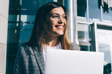 Skilled female freelancer in spectacles for vision correction from eye load smiling during remote...
