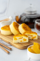 Beautifully decorated breakfast of pancakes with peach filling and peach slices, served with cup of tea on a wooden board. Concept of morning aesthetics, healthy breakfast and cosy home-cooked meals.