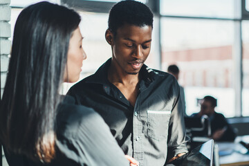 Male and female company workers communicated during break from collaboration with partners while reading business news via digital tablet, young colleagues discussing information and idea for project