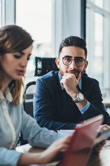 Fototapeta premium Portrait of caucasian business man in optical spectacles for provide eyes protection looking at camera while male and female colleagues making research of information for new starup IT project