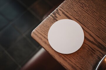 A white circle beer coaster mockup placed on a rustic wooden table.