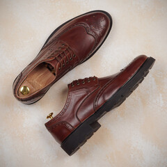 A pair of men's classic shoes made of brown leather on a colored background. Elegant fashion for a stylish man