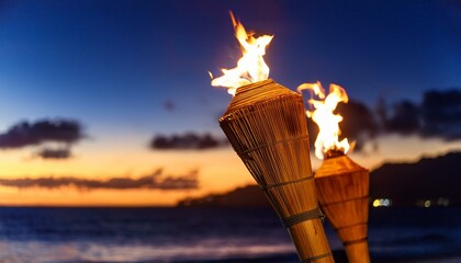 Multiple tiki torch with flame burning on the beach with a dramatic sunset in the background; tiki torch burning during sunset by the beach; beautiful resort by the ocean with tiki torches with flames