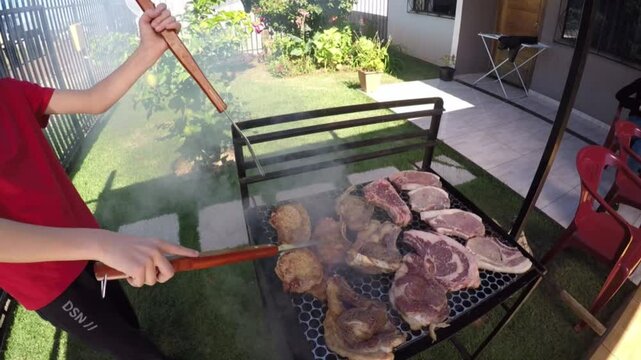 Menino assando carne em churrasqueira a