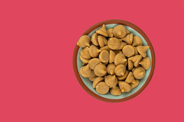 Overhead view of a small bowl filled with peanut butter baking chips on a red background.