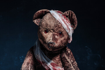 Old brown teddy bear wrapped in bloody bandages on a black background. Halloween concept