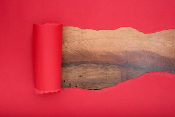 Torn red paper revealing a wooden background. Copy space.