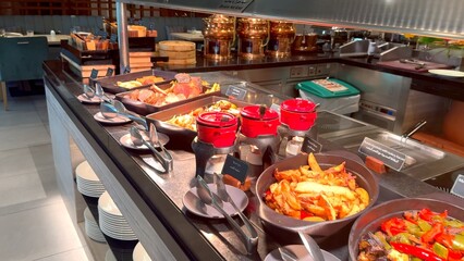 Buffet offering roasted vegetables in cast iron plates ,rich gravies ,perfectly cooked roasted beef. This restaurant spread is paired with clean plates for delightful and delicious dining experience.