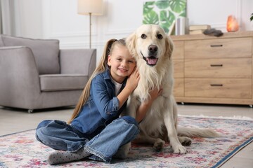 Girl with her cute Golden Retriever dog on rug at home