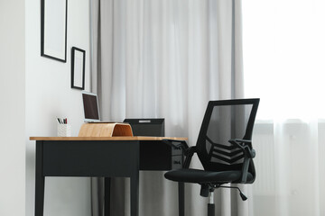 Black chair, laptop and desk in office
