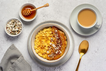 Food photography of millet porridge with caramelized banana, pecan, nuts, coconut flakes, chia, flaxseeds, honey, tea with almond milk