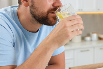 Man drinking water with lemon indoors, closeup