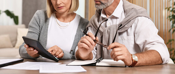 Pension savings. Couple planning budget at wooden table indoors, closeup