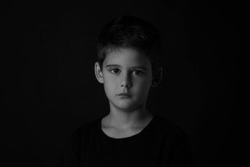 Fototapeta premium Portrait of sad little boy on dark background. Black and white effect