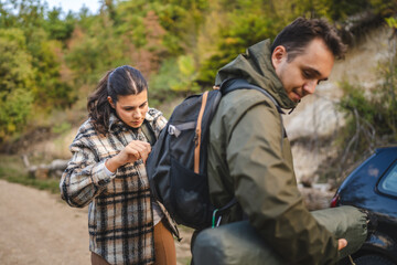 Fototapeta premium Girlfriend help boyfriend to pack and fasten his backpack
