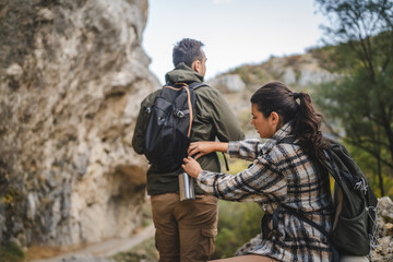 Girlfriend help boyfriend to pack and fasten his backpack