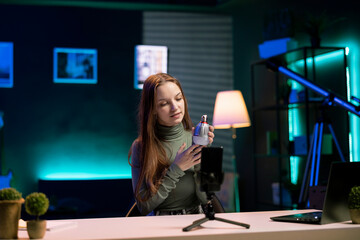 Influencer doing house improvement video vlog, showcasing newly released smart light bulb to viewers. Smiling content creator greeting subscribers. presenting WIFI home automation