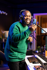 Professional artist producer recording his voice on microphone, improving the sound quality and...