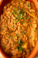 A bowl of lentil stew garnished with fresh herbs. Ideal for food blogs, vegan menus, or articles focusing on hearty, plant-based meals perfect for cooler seasons.