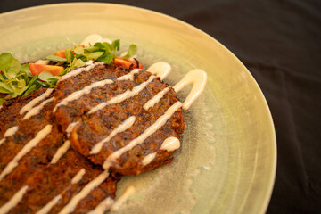 A close-up shot of crispy breaded veggie pancakes served with a tangy dipping sauce. Perfect for food blogs, menus, or vegetarian-themed content. It is ideal for showcasing light, crunchy appetizers.