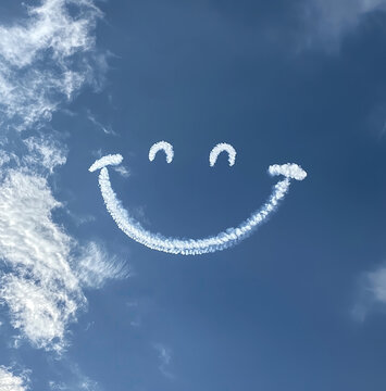 smiley face shaped clouds skywriting in the blue sky 