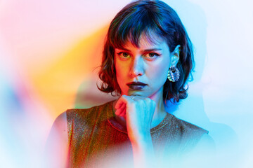 Young woman in colorful lighting contemplates thoughtfully
