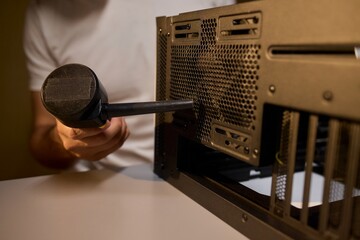 A man cleans a computer case with a vacuum in a bright room, stressing workspace tidiness