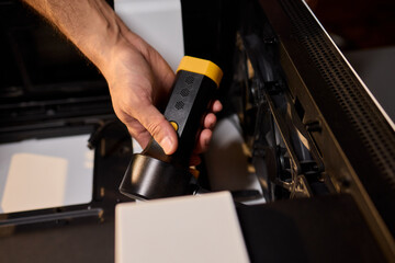 A man cleans a computer case with a vacuum in a bright room, stressing workspace tidiness