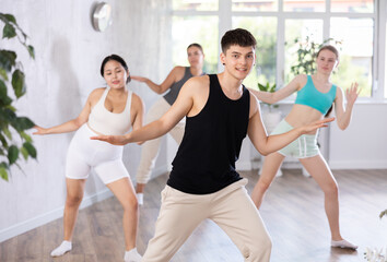 Fototapeta premium Happy young women and man wearing sportswear smiling dancing in fitness studio in morning.