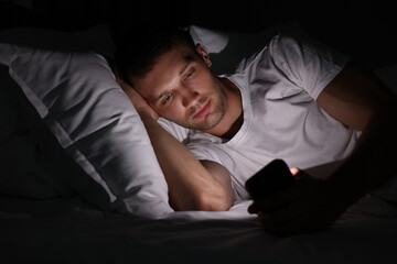 Fototapeta premium Bad habit. Man using smartphone in bed at night
