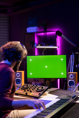Professional composer working with mixing console and electronic keyboard to follow online tutorial...