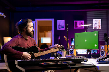 Beginner composer trying to tune his guitar strings for a new song, watching online videos on...