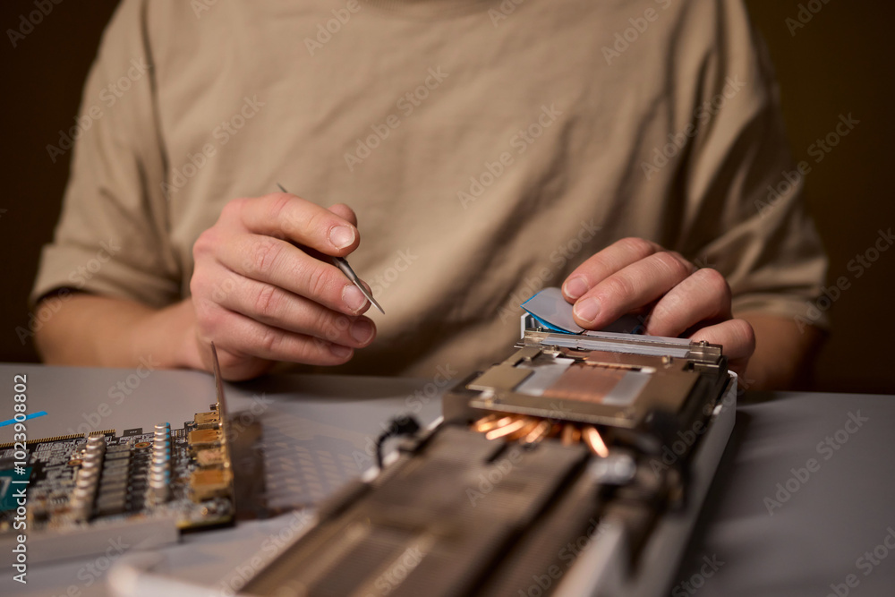Poster hand repairing a graphics card through the application of thermal paste for better performance