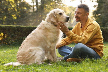 Smiling man with cute Golden Retriever dog on spring day