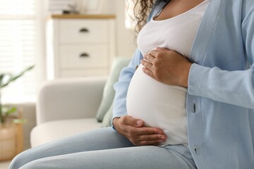 Pregnant woman on sofa at home, closeup