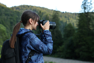 Photographer with backpack and camera taking picture of beautiful mountains, space for text