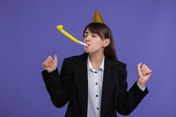 Woman in party hat with blower on purple background