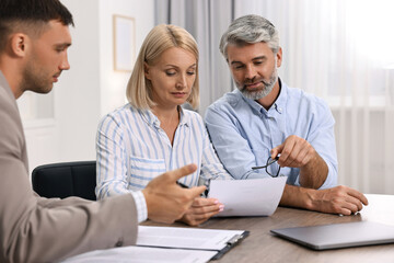 Fototapeta premium Pension plan. Couple consulting with insurance agent at table indoors