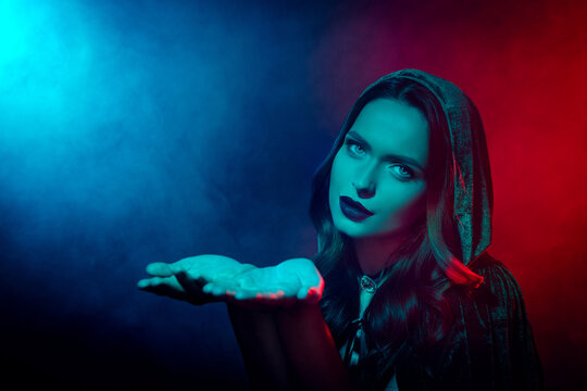 Photo of tempting lady in witch costume hold hands demonstrate copyspace for advertising isolated neon mist background