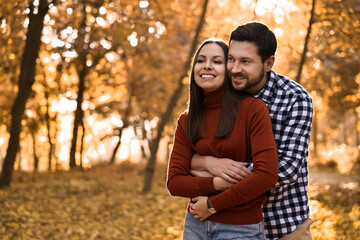 Fototapeta premium Beautiful couple spending time in park on autumn day, space for text