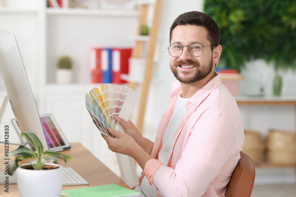 Poster designer working with color samples at table in office