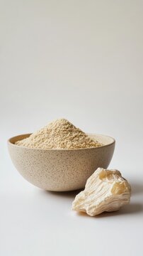 Vertical format, Natural herbal powder of Asafoetida Hing displayed in a simple bowl beside a raw root on a minimalist background indoors