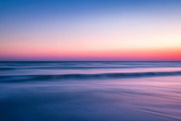 pastel sunset colors on ocean, horizon line in the middle of the frame.