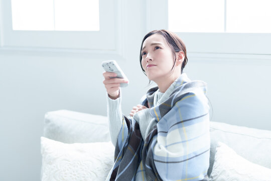 エアコンの温度を調整する女性