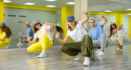 Teen girl in cap rehearses modern dances in dance hall