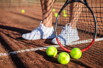 Tennis ball with rocket near grid at outdoor summer sunny court closeup