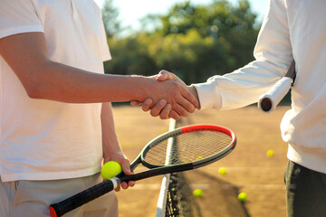 Two man tennis player shaking hands through grid playing tournament on sportive court closeup