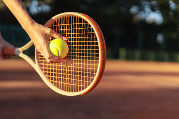 Woman tennis player tossing ball hitting racket at summer sunny outdoor court closeup