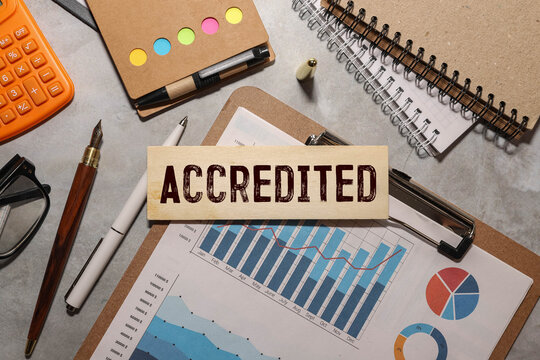 Businessman pressing his finger on the wooden cubes with the word accredited.